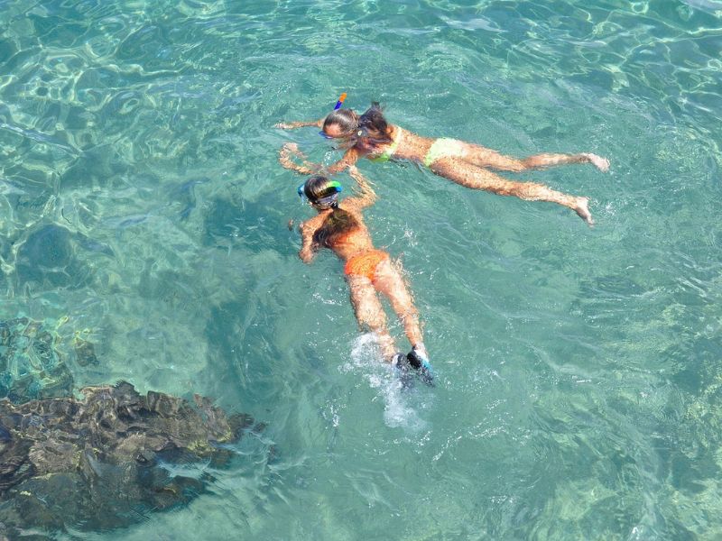 Mujer practicando snorkel entre arrecifes